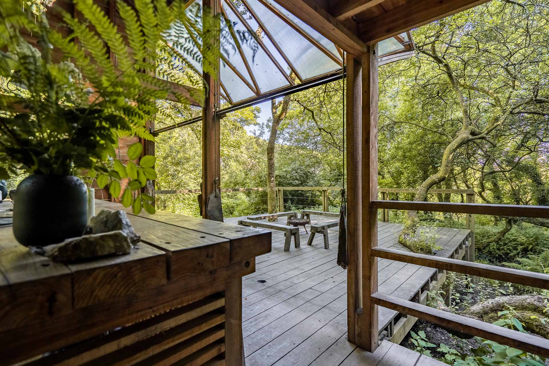 the private deck of the Danish Cabin, Kudhva, surrounded by lush green woodland