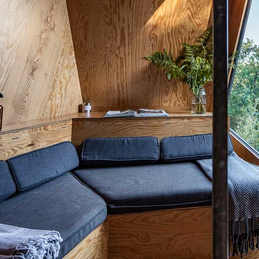 the interior of K3 Kudhva cabin, with a sofa and views through the window of woodland