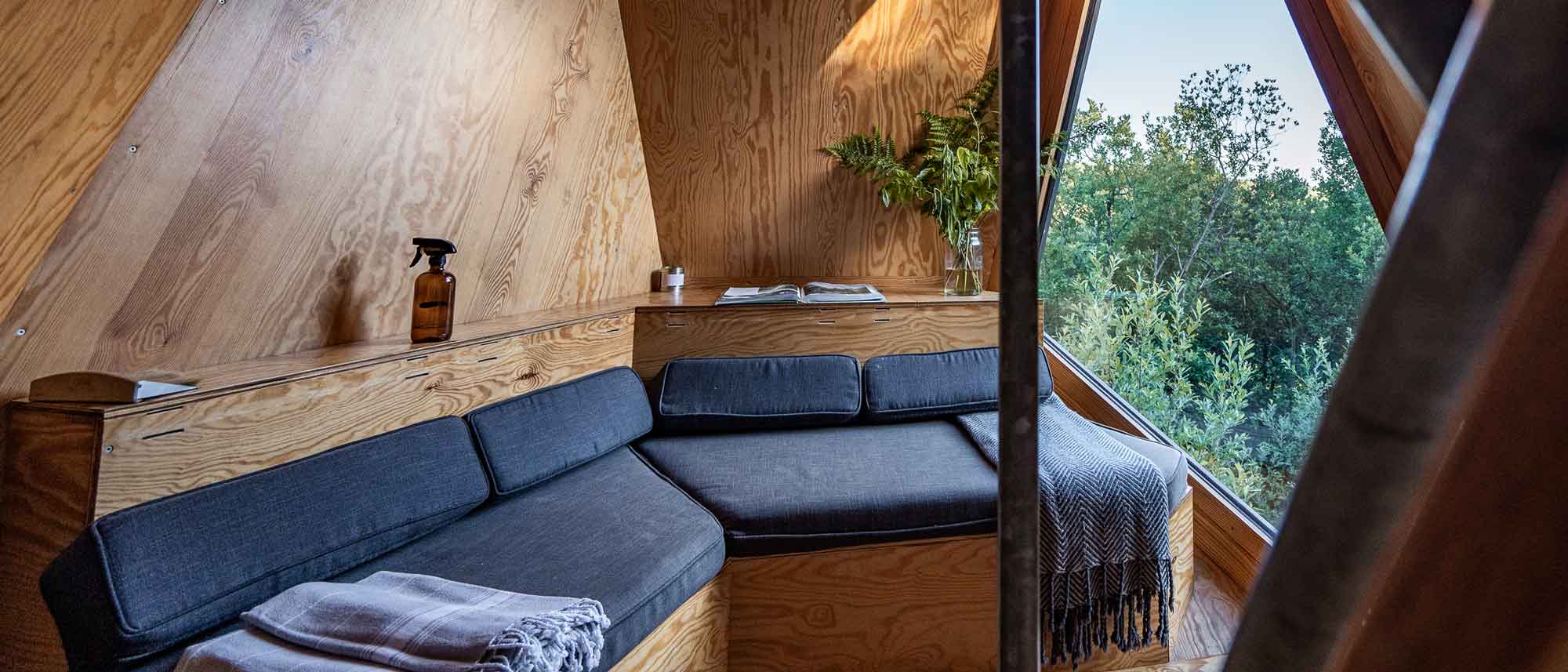 the interior of K3 Kudhva cabin, with a sofa and views through the window of woodland
