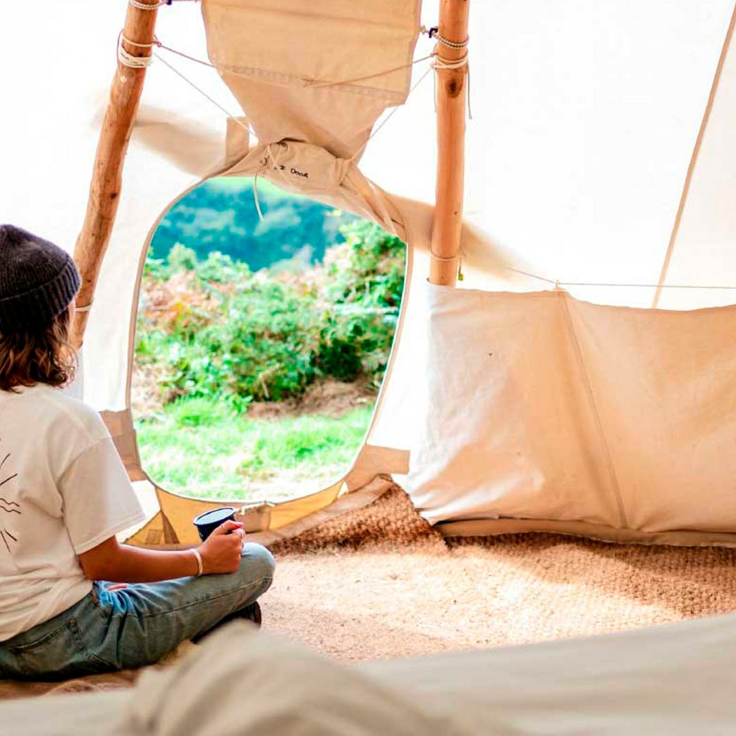 woman sitting peacefully in a comfortable, sustainable tipi at Kudhva campsite