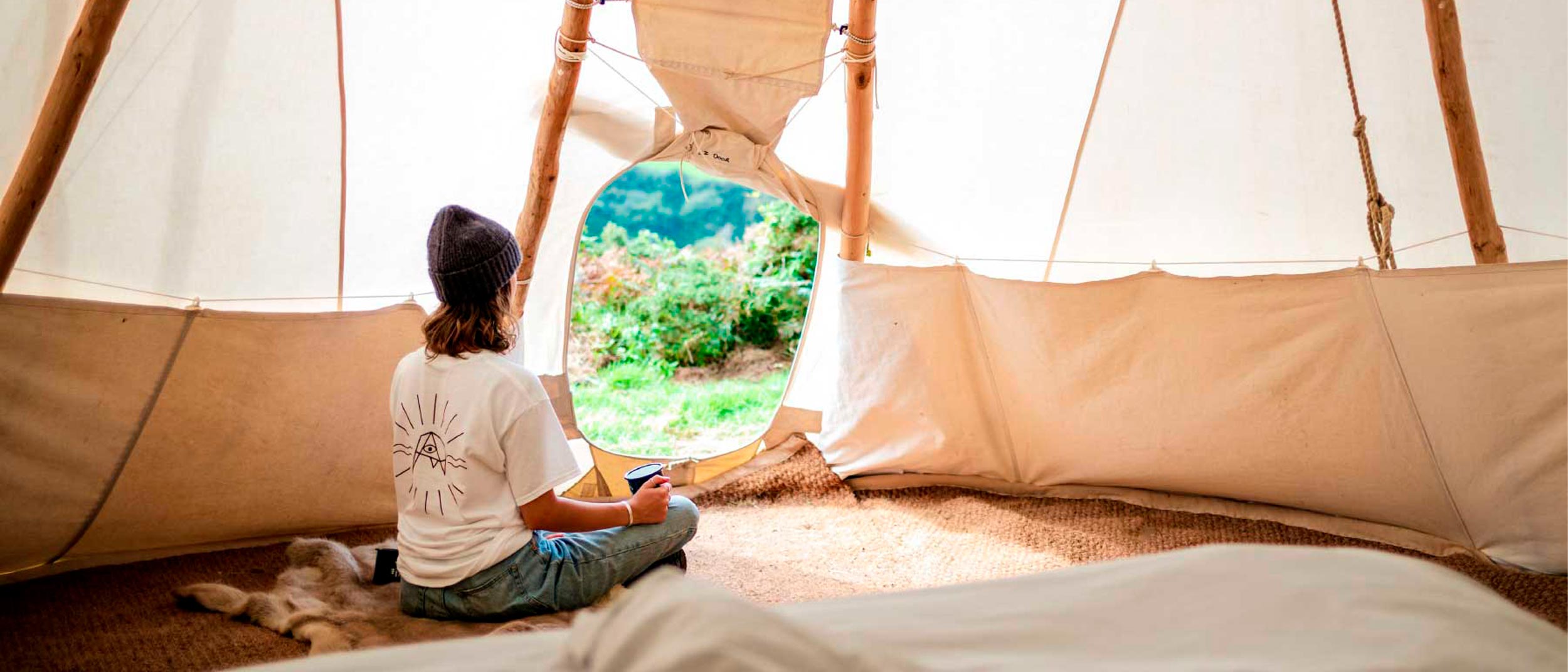 woman sitting peacefully in a comfortable, sustainable tipi at Kudhva campsite