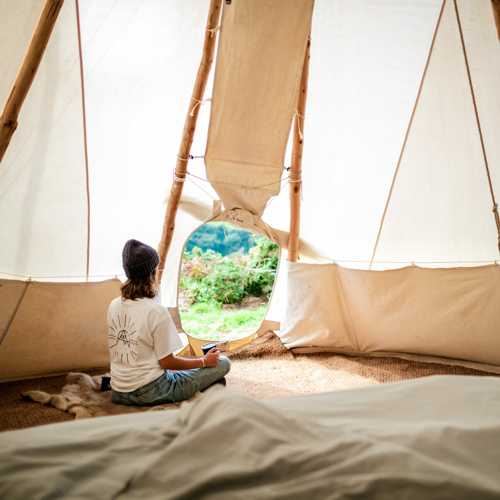 interior of a white canvas tipi, with a woman sitting peacefully