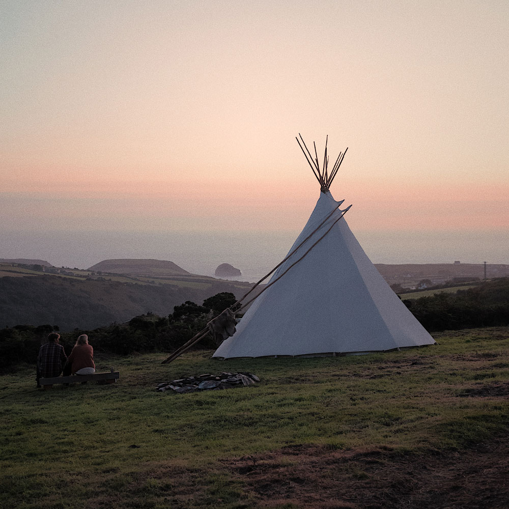 a white canvas tipi overlooking the sea at sunset, Kudhva, Cornwall