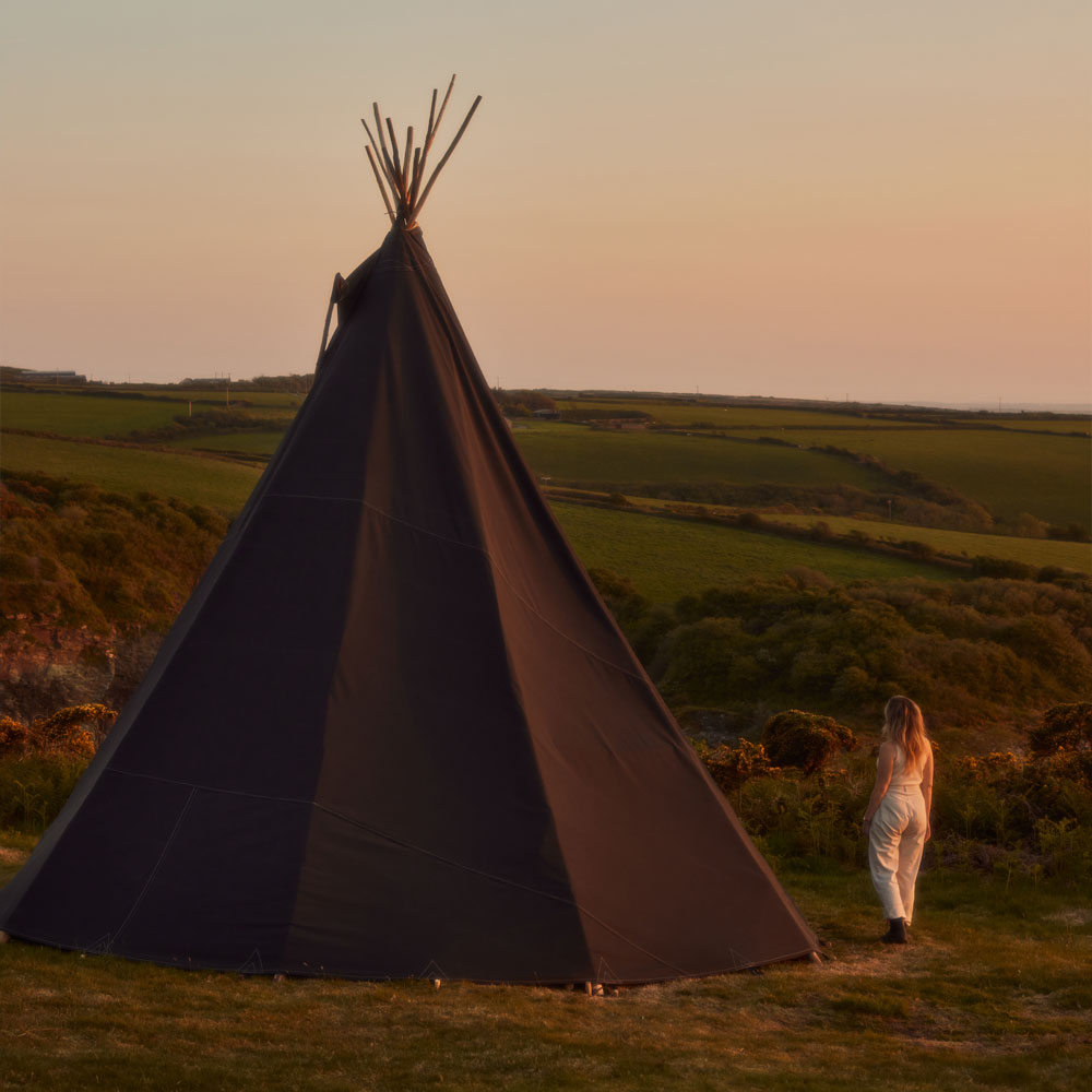 a black canvas tipi glowing in the sunset, Kudhva, off grid camping